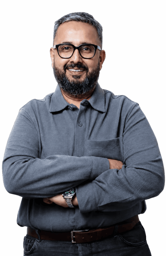 Portrait of a confident man with glasses and a beard, smiling in a professional setting.
